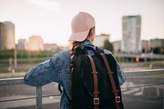 Photo tourist admires the overview of the sights of the city woman with backpack enjoy beautiful city view traveler mock up top of the city