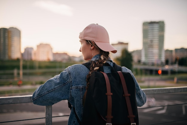 Photo tourist admires the overview of the sights of the city woman with backpack enjoy beautiful city view traveler mock up top of the city