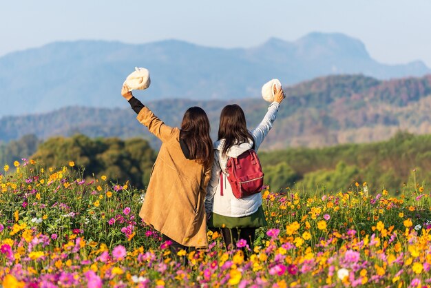 Tourist asian woman relax and freedom in beautiful blooming cosmos flower garden. Travel and Lifesty