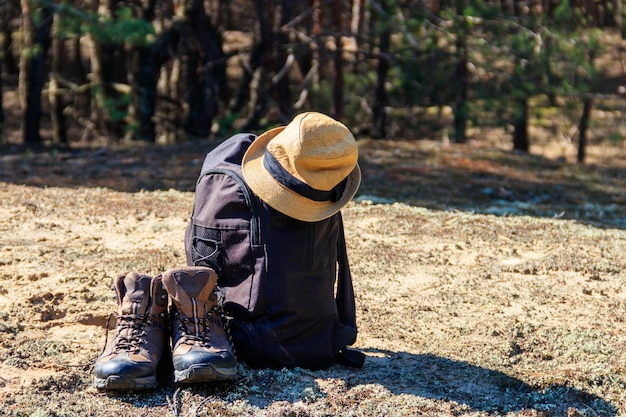 Tourist backpack hiking boots and hat on the glade in pine forest Hike concept