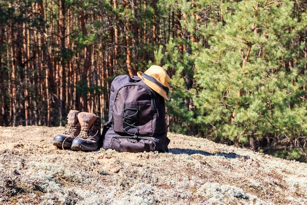 Tourist backpack hiking boots and hat on the glade in pine forest Hike concept