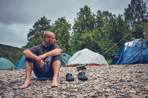 Uomo barbuto turistico che riposa sul fiume. fermati e rilassati viaggiando nella natura.