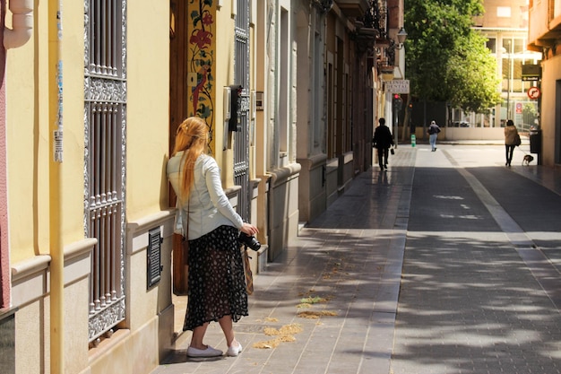 写真 写真を撮って通りを歩いている観光ブロンドの女性