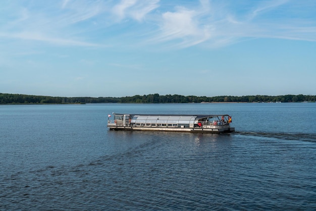 A tourist boat sails on Lake Senftenberg Germany Calm water Green forests on the coast Blue sky