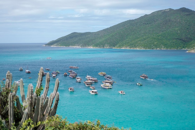 tourist boats in ocean with azure water against a background of green mountains and cacti