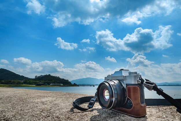 Photo tourist camera placed on the cement floor with the sky and the sea as the background