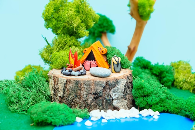 Tourist camp Plasticine landscape with a tent a campfire and a backpack in the middle of the forest The concept of ecofriendly recreation and environmental protection