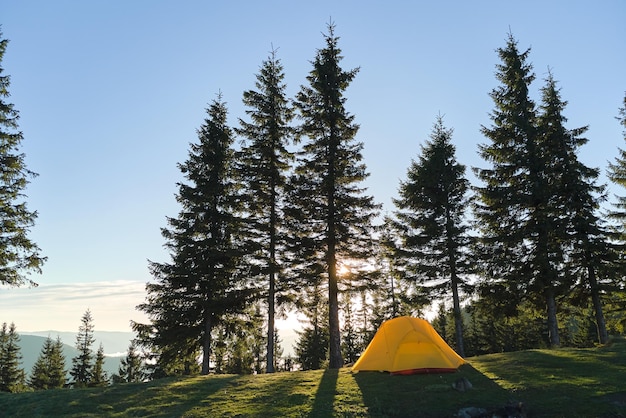 Tourist camping tent on mountain campsite at bright sunny evening. Active tourism and hiking concept.