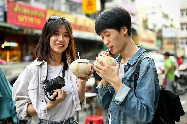 A tourist couple enjoying their fresh coconut drink at a Chinatown in Chiang Mai