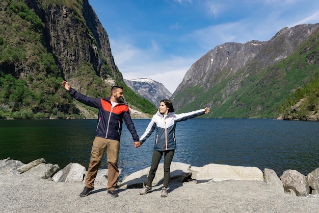 Tourist couple at the foot of the fjord and surrounded by high mountains in Gudvangen Norway