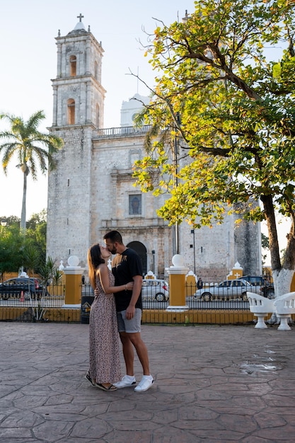 Photo tourist couple kissing in front of san servacio church in valladolid mexico