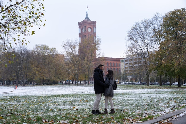 Tourist couple in love in the park in front of the Rotes Rathaus in the city Berlin with the snowy picture