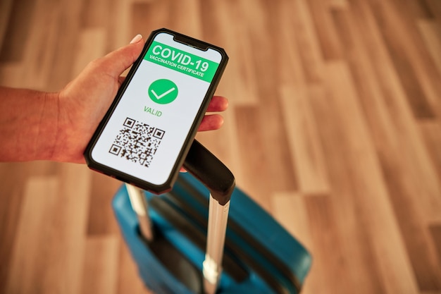 Tourist Covid-19 vaccination certificate with QR code and a suitcase