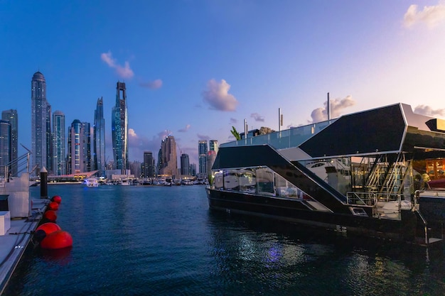 Tourist cruise ferry boat near pier in Dubai Marina harbor Beautiful night view of Dubai marina UAE