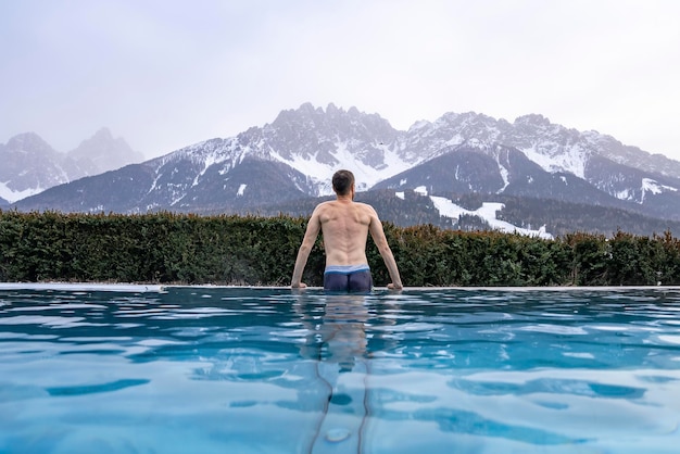 Tourist enjoying in swimming pool while looking at mountain range during winter