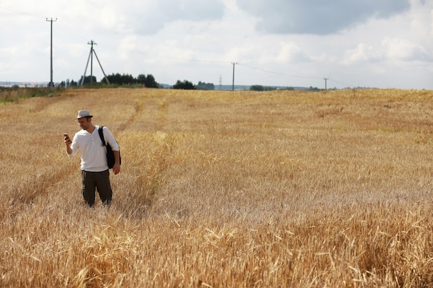 Tourist in a field of cereal plants. A man in a wheat field. Grain harvest.