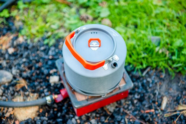 Tourist gas kettle in nature a kettle boiling on a camping stove to make tea while camping