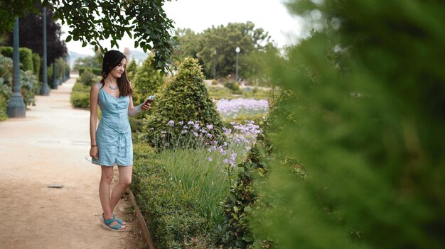 파란색 드레스를 입은 관광 소녀가 가이드북을 보고 경로를 찾고 있습니다. 따뜻한 기후