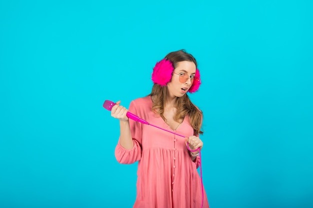 tourist girl in a pink dress in pink headphones with a pink microphone