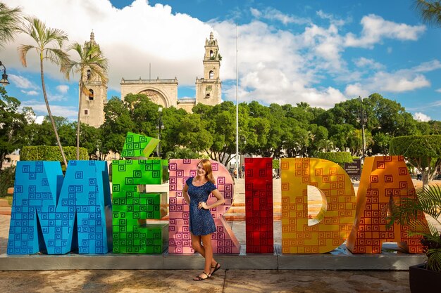 A tourist girl stands near the capital letters - of the name of the city of Merida. Mexico