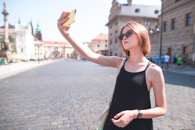 観光女の子は古い建築の背景にselfieを取る