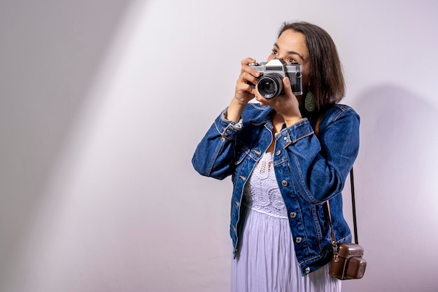 Tourist girl taking pictures with her retro camera travel concept white background