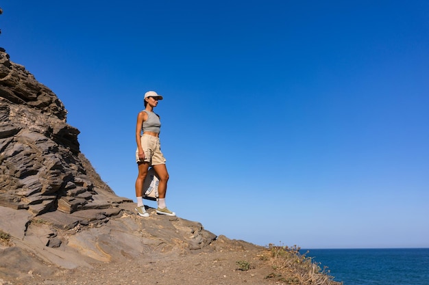 Photo tourist girl with a backpack on her back in the summer stands on top of a mountain