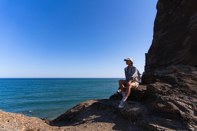 Photo tourist girl with a backpack rests in summer sitting on top of a mountain