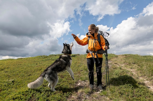 Tourist girl with her friend Siberian husky dog hiking in the green mountains