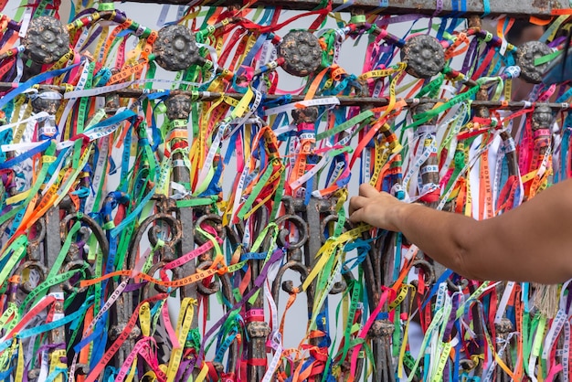 Tourist hands tying souvenir ribbons on the railing of the Senhor do Bonfim church in the city of Salvador Bahia