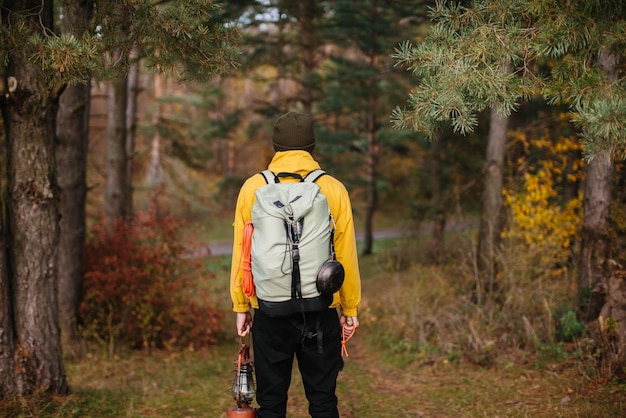 Tourist on a hiking trail in the forest with a backpack and a lamp