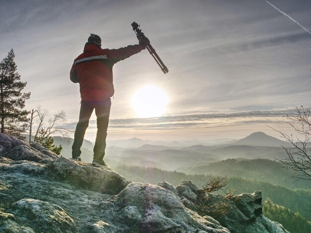 写真 観光旅行のトリポッド写真家が山から日の出を撮影するためにピークに登った