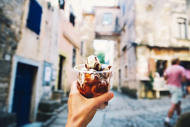 Photo tourist holds in hand fritule doughnuts balls with chocolate homemade fritters