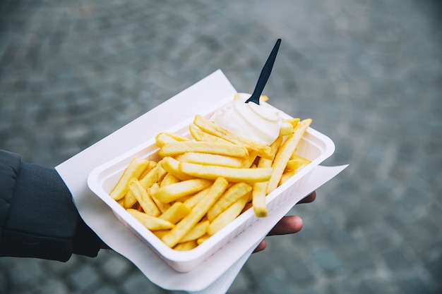 Tourist holds popular street junk food  French Fries in Holland Amsterdam Netherlands