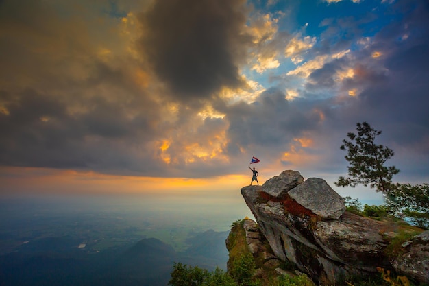 Турист смотрит на тайский флаг на вершине холма в Таиланде
