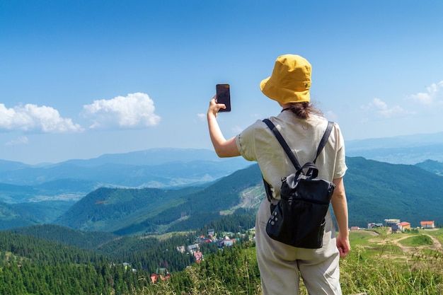 A tourist is relaxing in nature and uses the Internet on a smartphone The girl traveler photographs