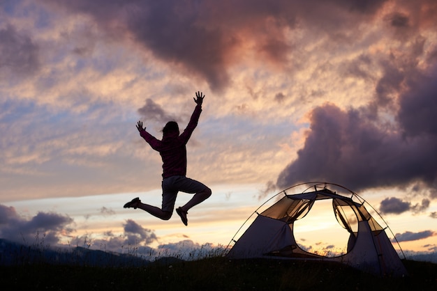 Tourist jumping high adoring beautiful scenery around on moutain hill