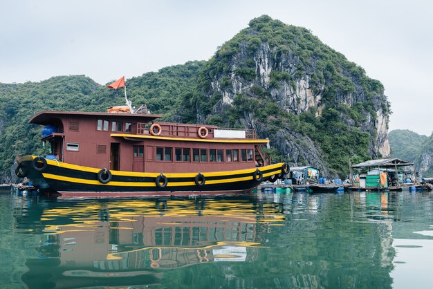 Tourist Junks (boats) and Floating village in Ha long Bay, Vietnam. Picturesque sea landscape with reflection