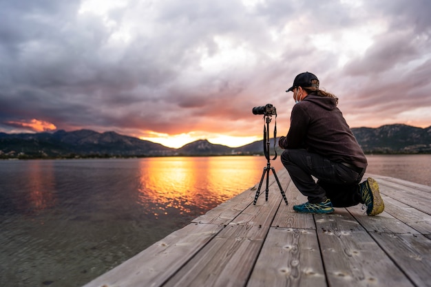 A tourist keen on photography bends down to adjust his camera to get a good picture