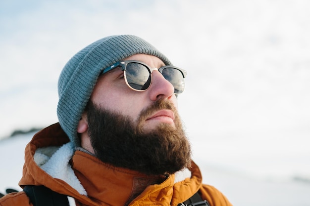 A tourist looks at the sunset while climbing in the winter mountains in glasses reflecting the sky