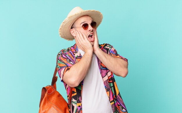 Tourist man feeling happy, excited and surprised, looking to the side with both hands on face