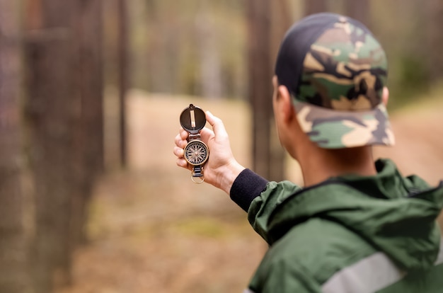 Tourist man is searching right direction using compass in forest