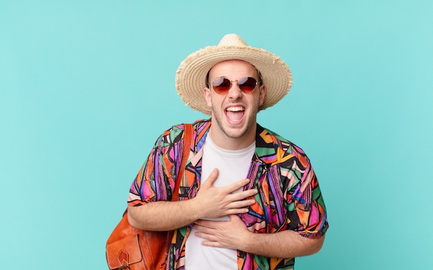 Tourist man laughing out loud at some hilarious joke, feeling happy and cheerful, having fun