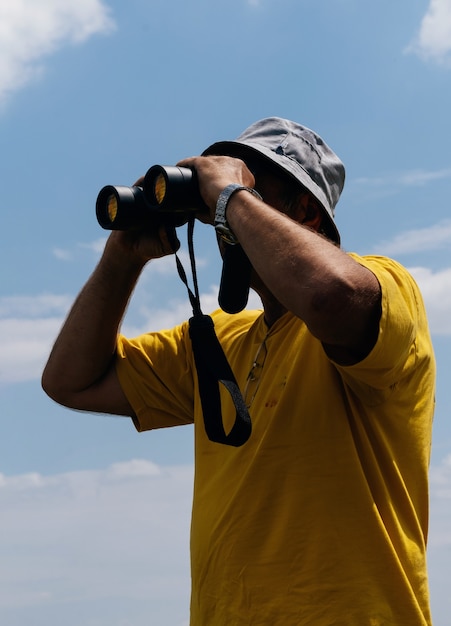 Foto uomo turistico che guarda attraverso il binocolo