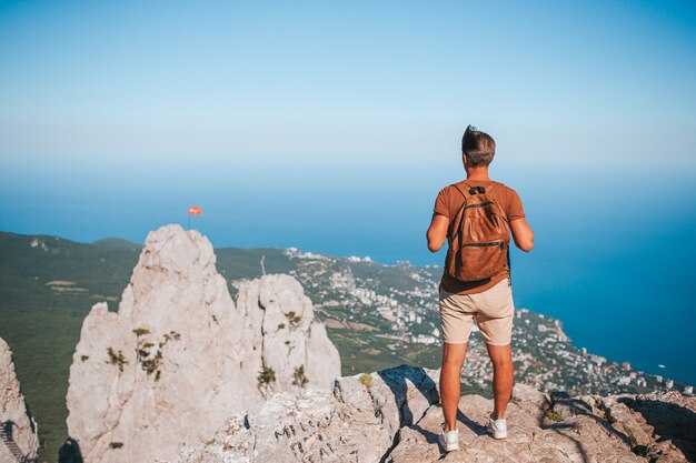 Uomo turistico all'aperto sul bordo della scogliera in riva al mare