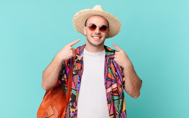 Tourist man smiling confidently pointing to own broad smile, positive, relaxed, satisfied attitude