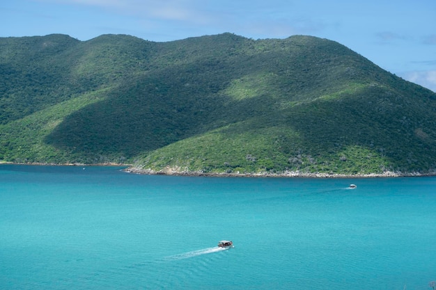 Tourist motor boat float on blue water against the background of green mountains