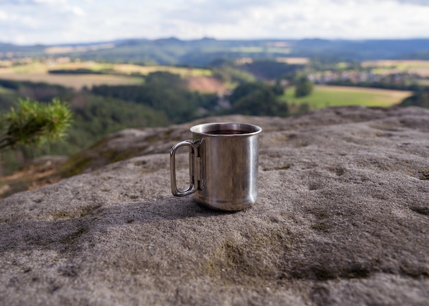 Photo a tourist mug stands on a stone against the backdrop of mountains in the national park of saxon swit