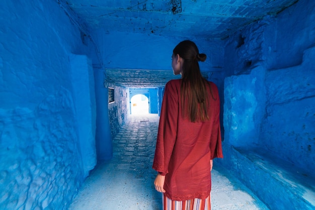 Tourist in national dress of the east stands in the tunnel of the blue city of morocco