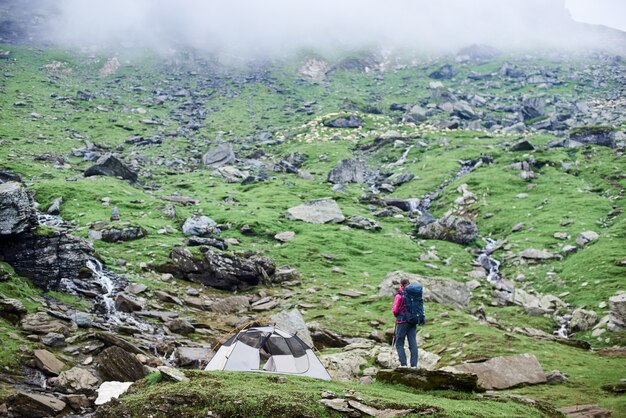 Turista vicino ad una tenda sul pendio roccioso